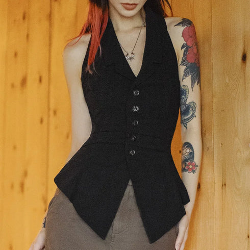 Person wearing a black vest with tattoos on arms against a wooden background